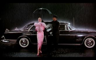 in una breve sequenza vediamo una donna di gran classe uscire da un'automobile avvolta in un manto color rosa bordato di pelliccia